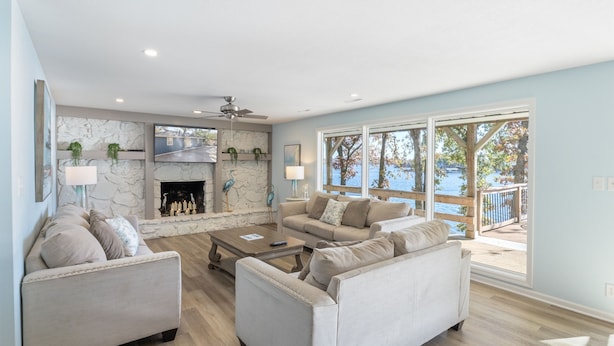 A spacious living room with a fireplace, two sofas, a coffee table, and large windows offering a view of the outdoors.
