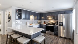 A modern kitchen with dark cabinets, stainless steel appliances, and a central island with bar stools. - Sunset & Lake Views, Kayak, Outdoor Dining & Seats (Gravois Mills)