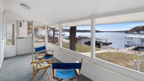 A covered balcony with a view of a lake, wooden chairs, and a small table. - Sunset & Lake Views, Kayak, Outdoor Dining & Seats (Gravois Mills)