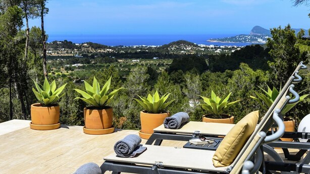 Una terrazza con vista sul mare, arredata con poltrone relax e piante in vaso.