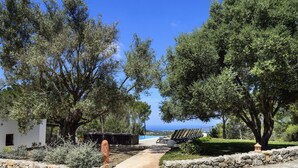 Un sentiero conduce a una zona piscina con lettini e vista sul mare.