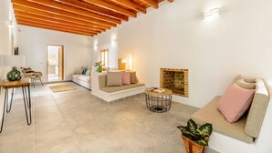 Un soggiorno spazioso con un soffitto alto in legno, un caminetto, un divano, un tavolino da caffè e un'area pranzo con tavolo e sedie.