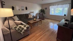 A living room with a sofa, armchair, coffee table, and a TV stand.