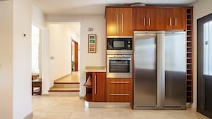 Eine moderne Küche mit Holzausstattung, einem Edelstahlkühlschrank, einer Mikrowelle und einem Backofen.
