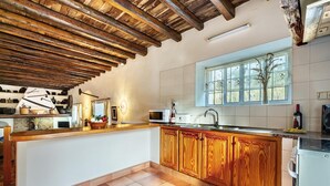 A kitchen with wooden cabinets, a microwave, and a window with a view of trees.