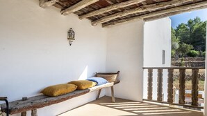 A balcony with a wooden bench, cushions, and a lantern.