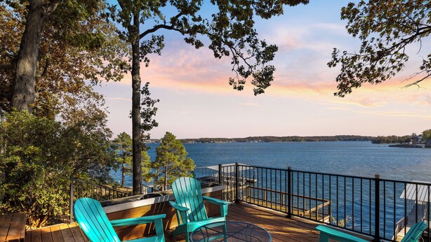 Una terraza con sillas Adirondack y una mesa con vista al lago.