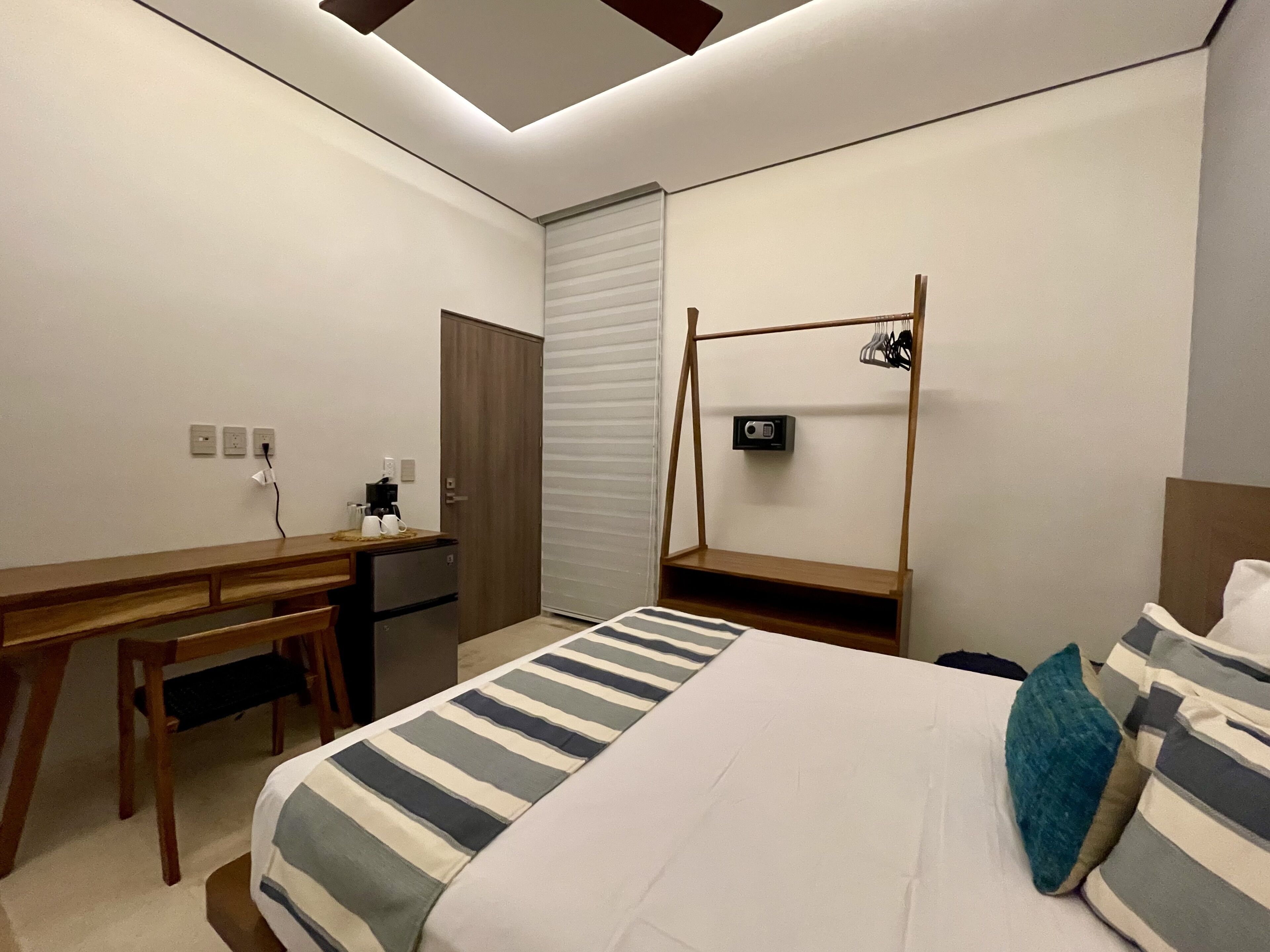 A modern hotel room with a bed, a desk, and a wardrobe.