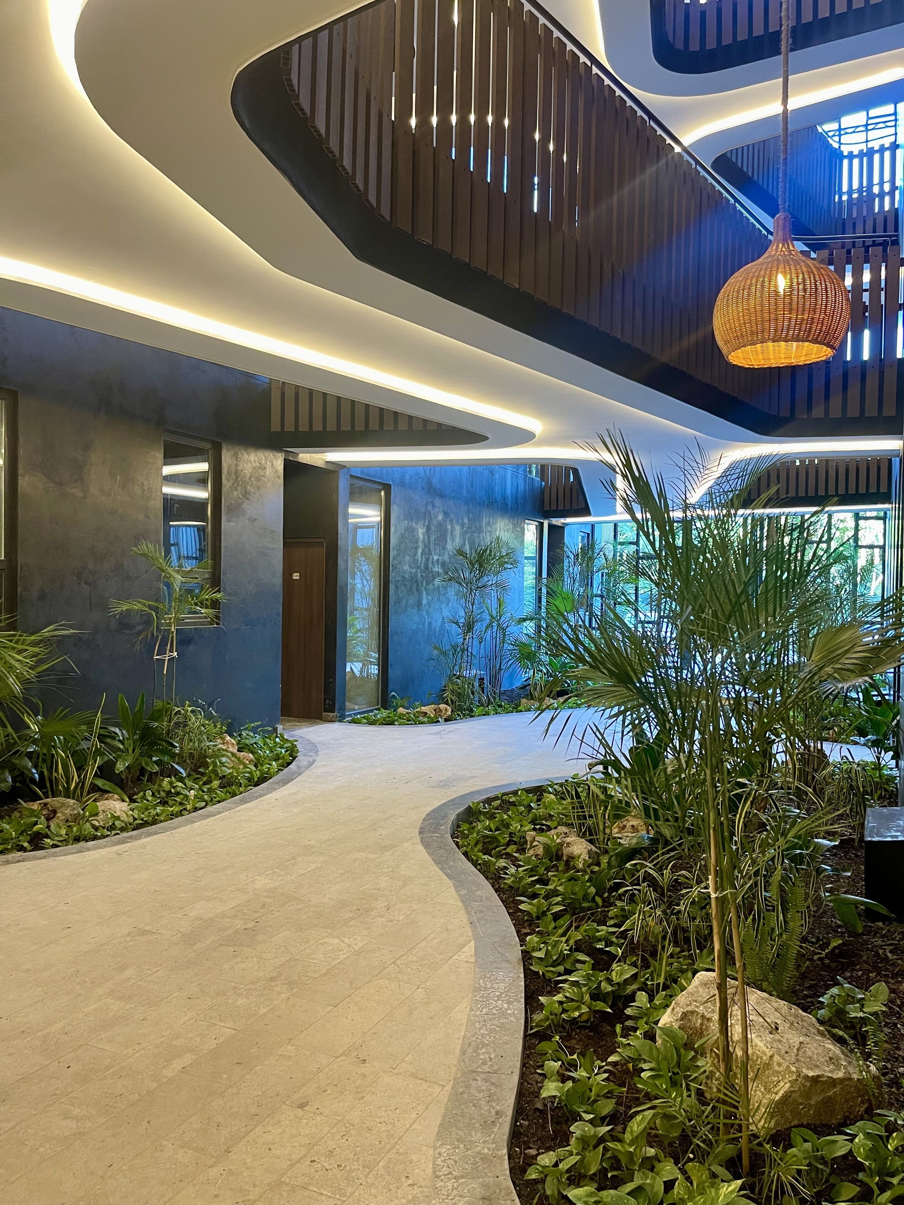 A modern interior with a curved pathway, wooden accents, and a hanging light fixture.