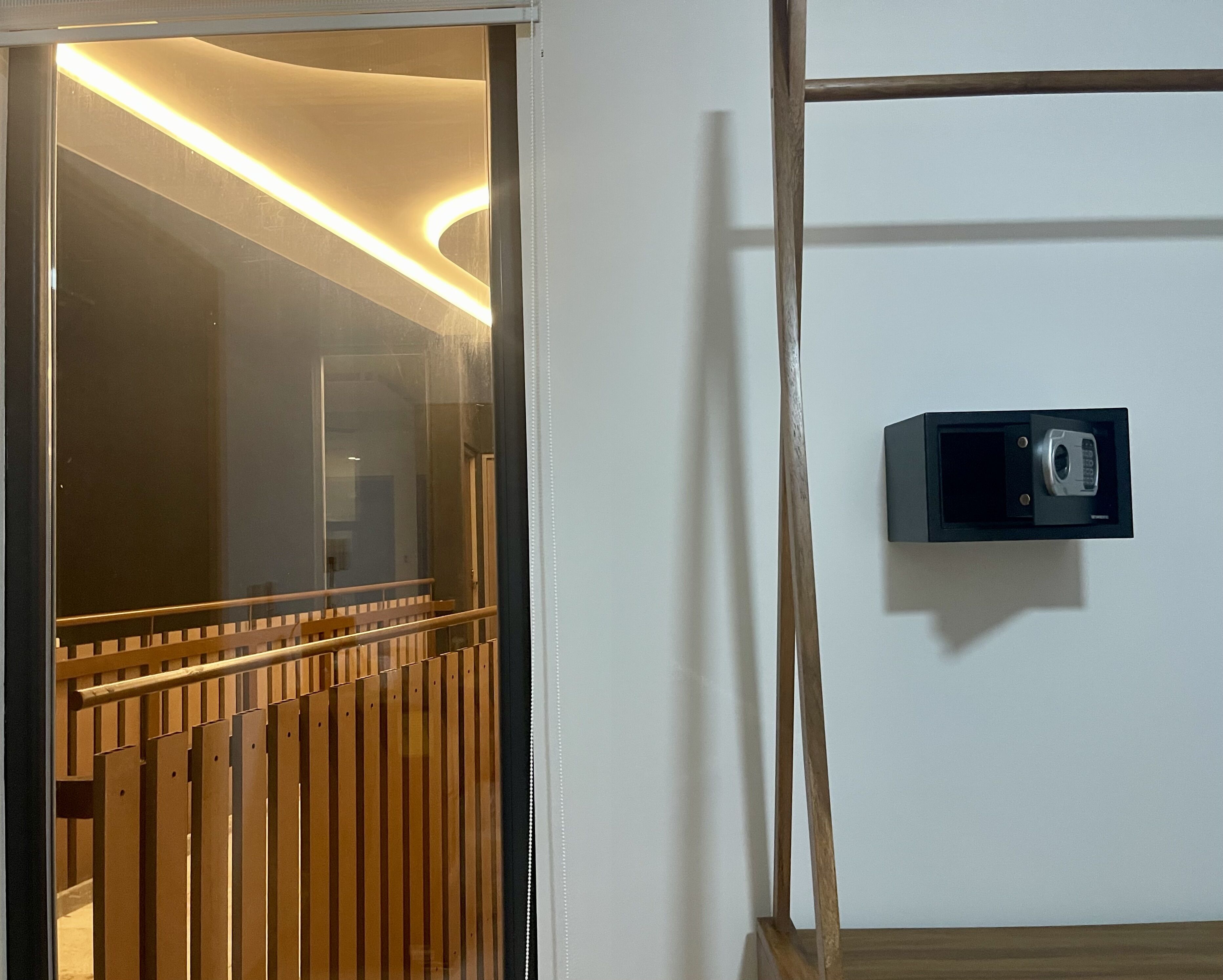 A room with a wooden slatted door, a wall-mounted intercom, and a wooden floor.