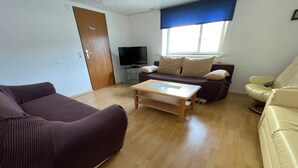 A living room with a brown sofa, a beige sofa, a wooden coffee table, and a television on a stand. - Apartment Beny (Bad Bellingen)