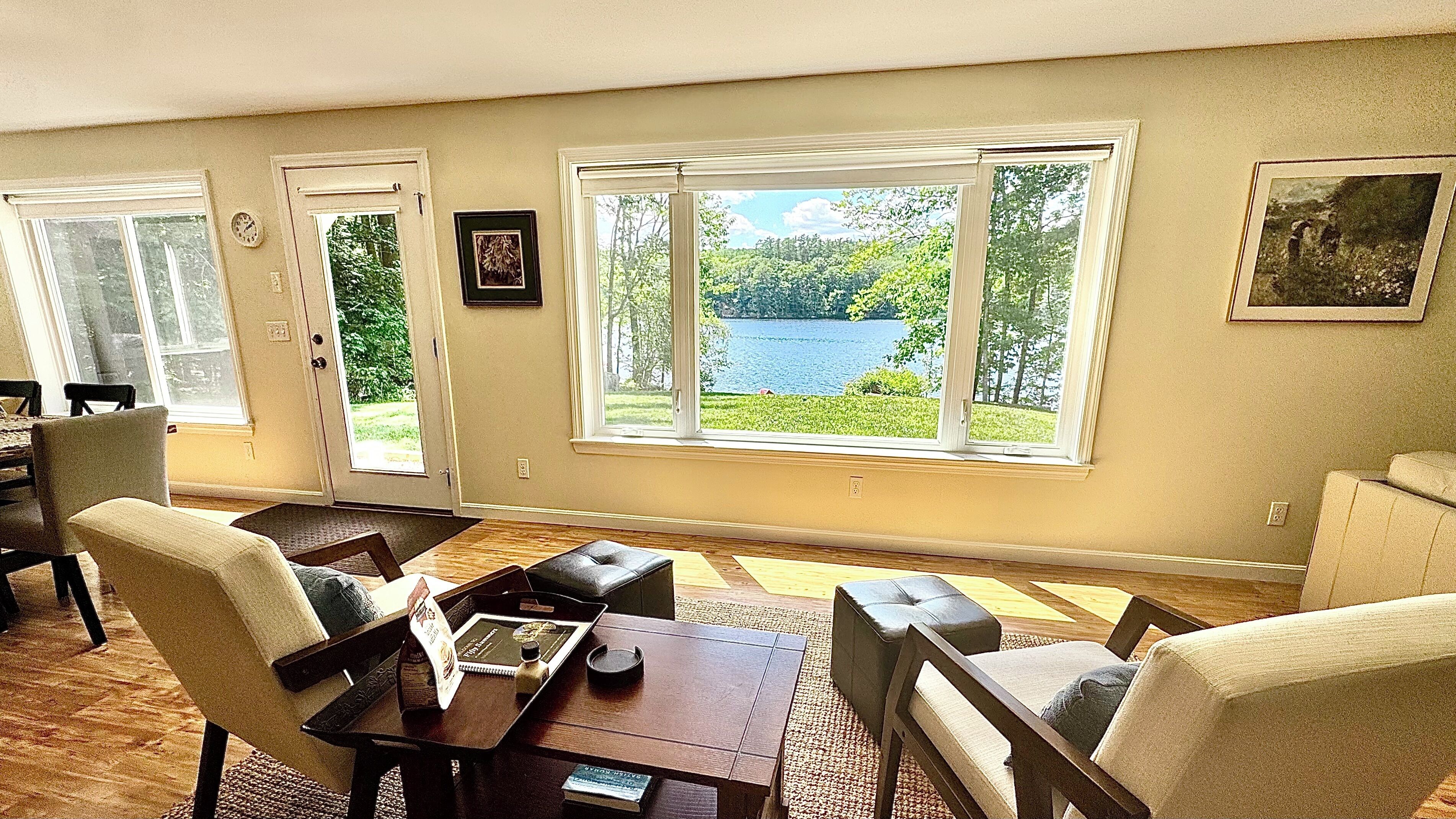 Ein Wohnzimmer mit Seeblick, ein Essbereich mit Stühlen und ein Couchtisch.