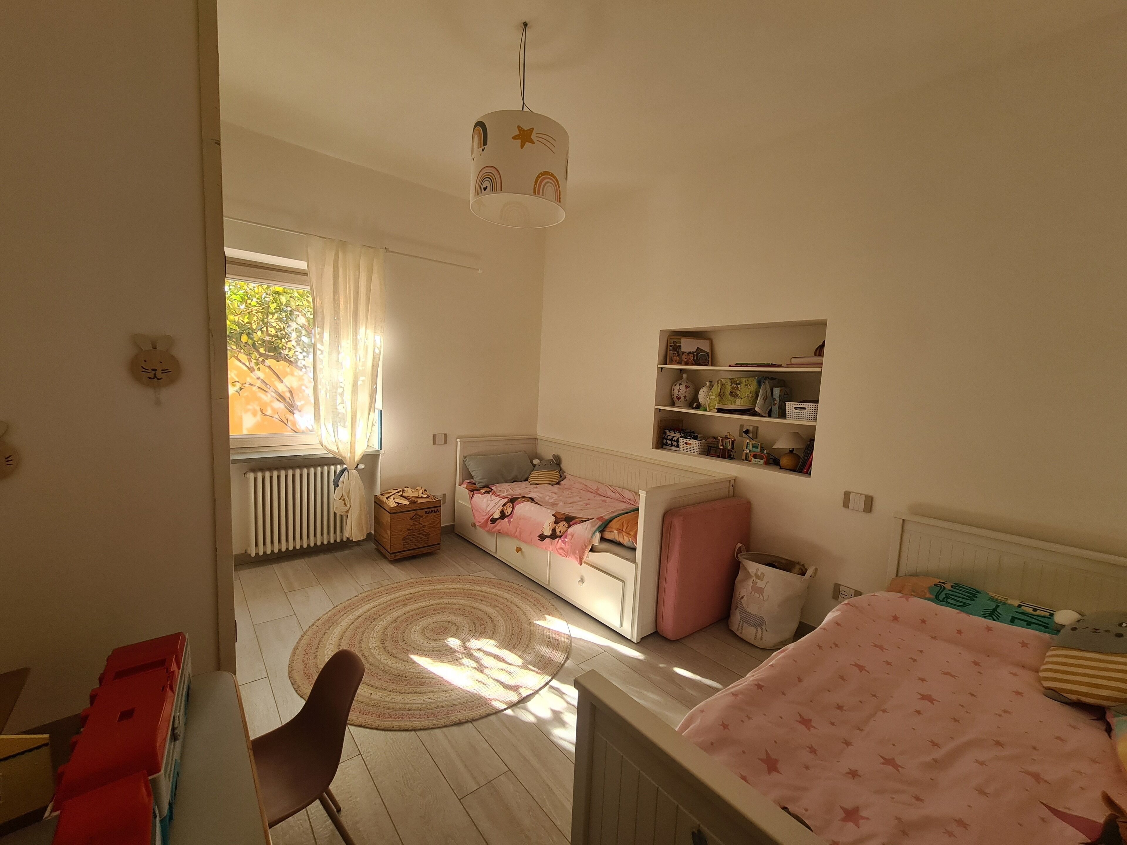 A child's bedroom with a bunk bed, a desk, and a radiator.