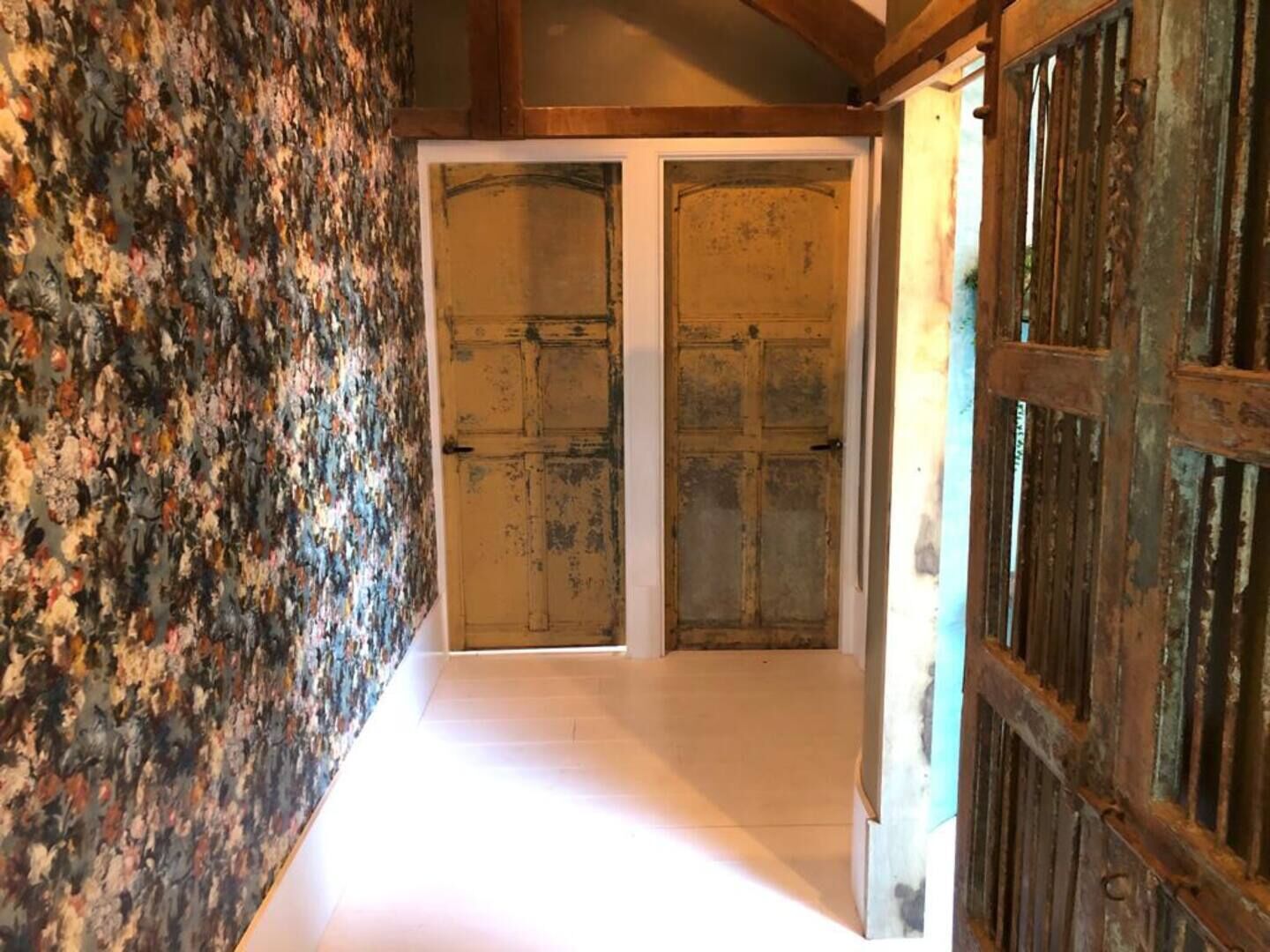 A hallway with a rustic wall and a wooden door.