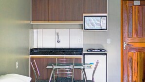 A compact kitchen with wooden cabinets, a microwave, and a small refrigerator. - Pinheiro Flat Hotel (Ibiapina)