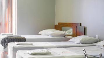 A hotel room with two single beds, a wooden headboard, white bedding, and a window with curtains.