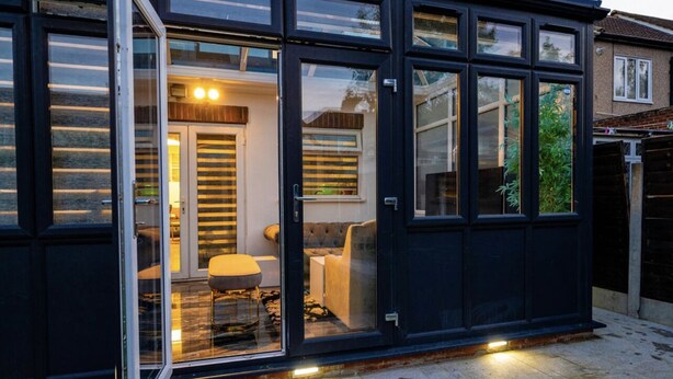 Una casa moderna con amplios ventanales que dan a una sala de estar con un sofá y una mesa.