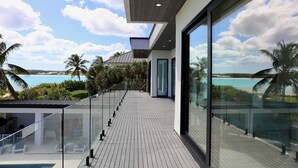 Een modern balkon met uitzicht op de oceaan en palmbomen.