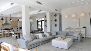 Een moderne woonkamer met een grote hoekbank, een salontafel en een eethoek met stoelen en een tafel.
