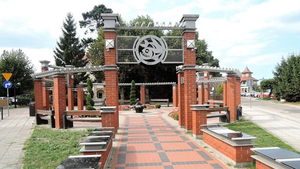 A brick pathway leading to a gated entrance with a decorative archway. - Holiday home in Niechorze with garden (Niechorze)