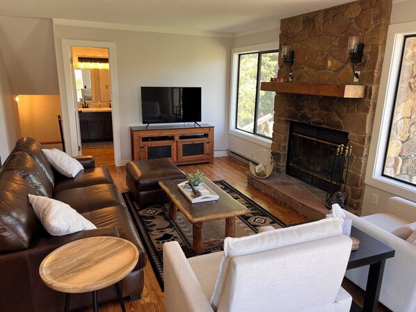 A living room with a stone fireplace, leather sofa, and a television.