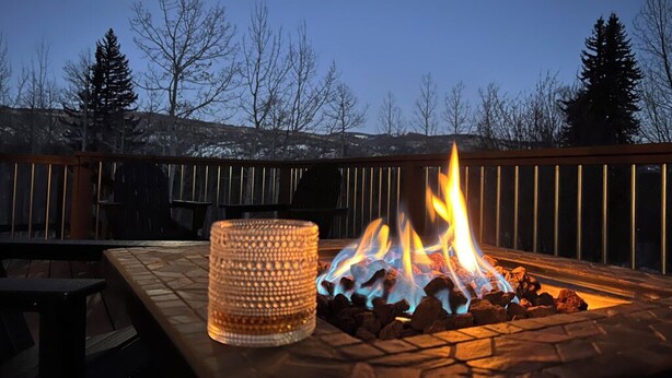 Een terras met een vuurkorf van steen en een kandelaar van glas.