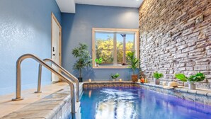 A swimming pool with a stone wall and a window with a view of trees. - Enchanted Forest Hideaway by Ghosal Luxury Lodging (Sevierville)