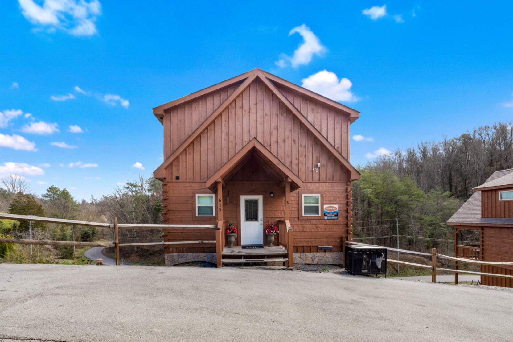 A wooden cabin with a front porch, a door, and a small sign on the side.