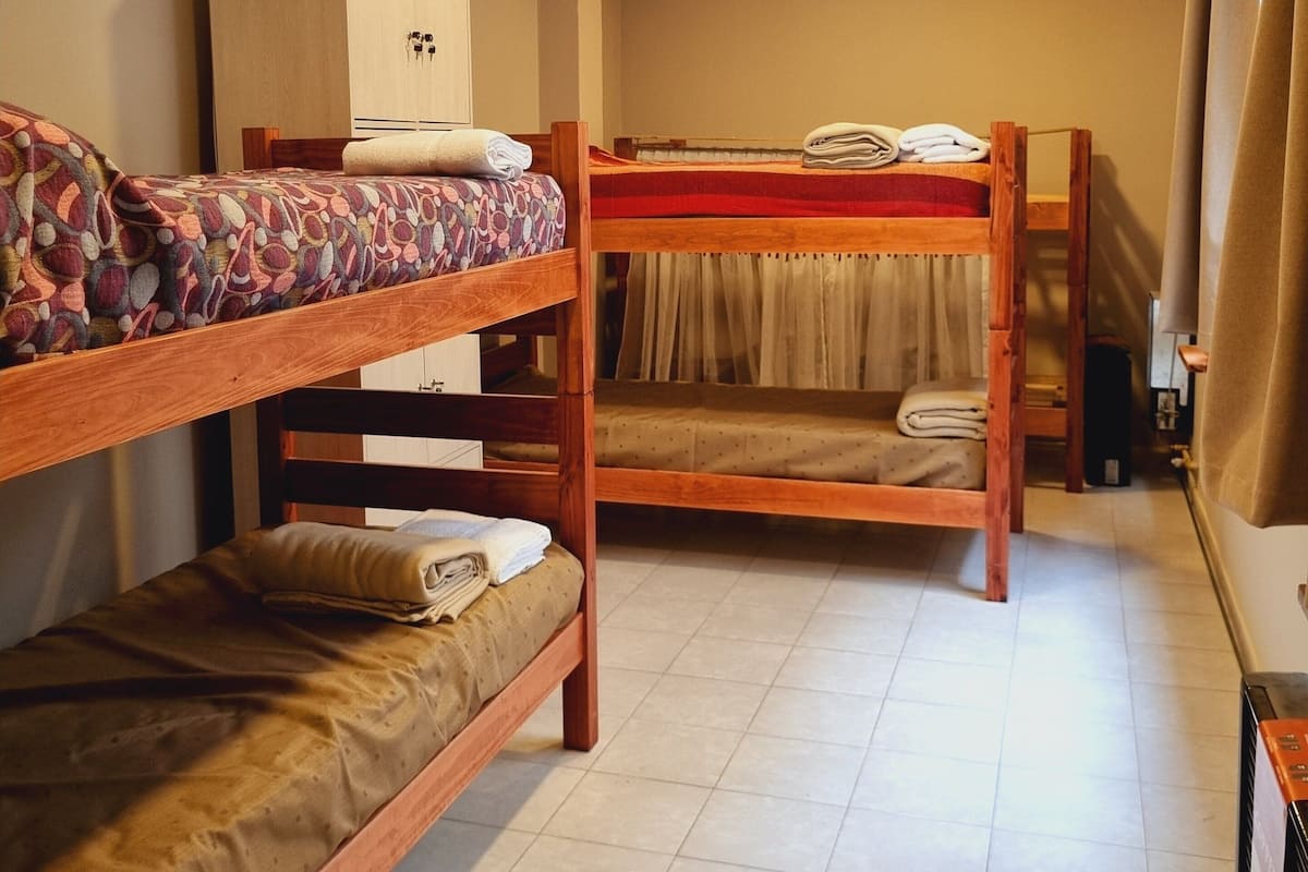 Ein Schlafsaalzimmer mit Etagenbetten, einem Kleiderschrank und einem Schreibtisch.