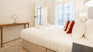 Une chambre d’hôtel avec un grand lit, une table de chevet avec un miroir et une vue sur les bâtiments par les fenêtres.
