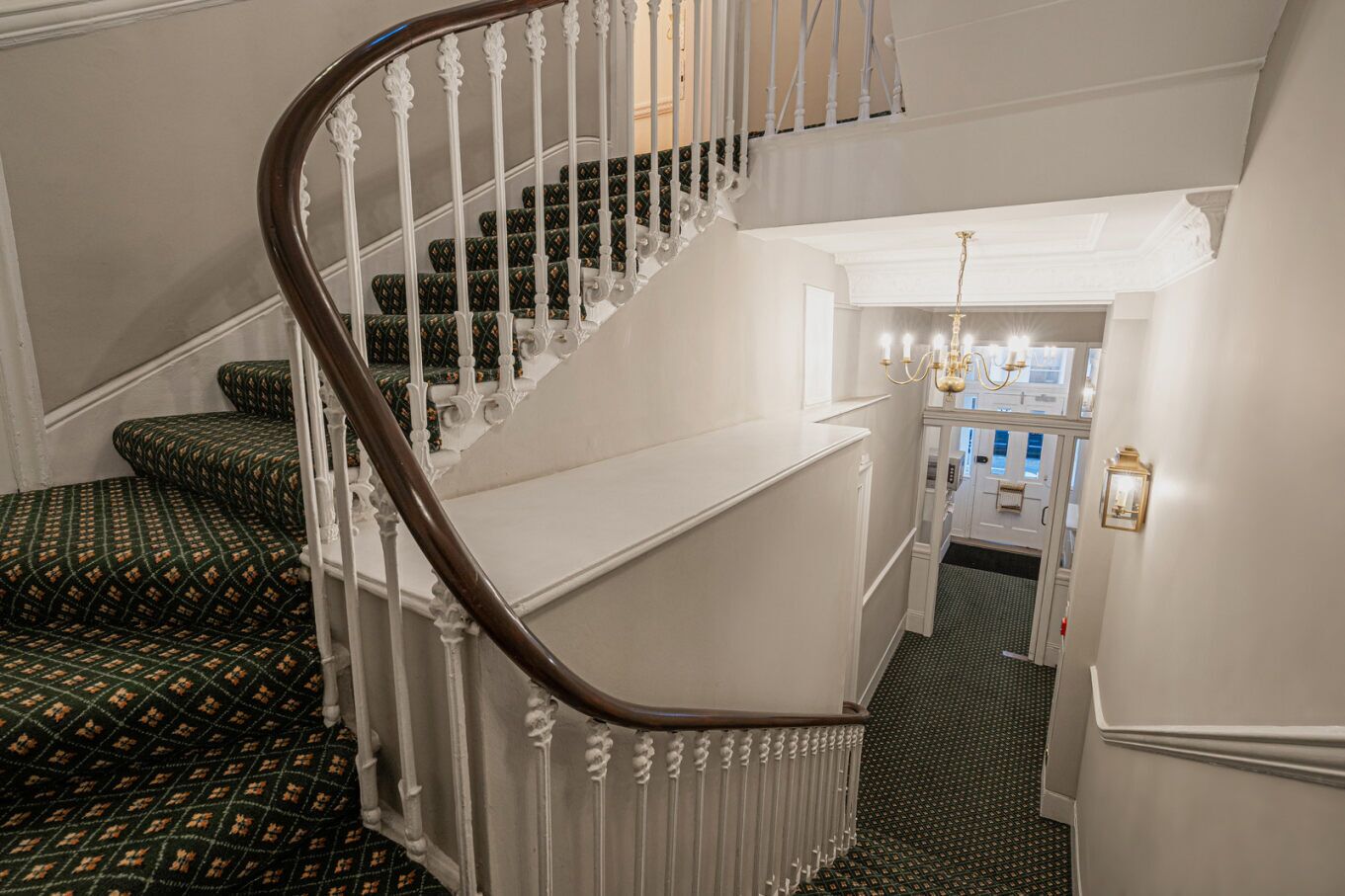 A grand staircase with ornate white railings and patterned carpeted steps.