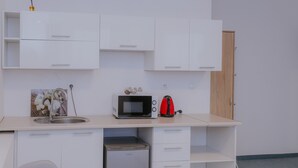 Een kleine keuken met een magnetron, waterkoker en een koelkastje.
