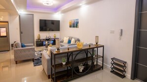 A modern living room with a sofa, coffee table, and TV. - The Luxurious Chateau (Kingston)