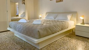 A modern bedroom with a large bed, a bedside table with a lamp, and a wall-mounted abstract art piece. - Splendid "True Venice Apartment" overlooking water (Venezia)