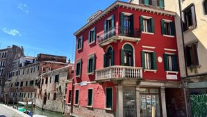 A red building with a balcony and a shop entrance. - Splendid "True Venice Apartment" overlooking water (Venezia)