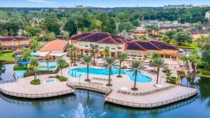 A resort with multiple swimming pools, palm trees, and a lake. - Beachside Vibes |2BR/2BATH Townhouse | Near Disney (Kissimmee)
