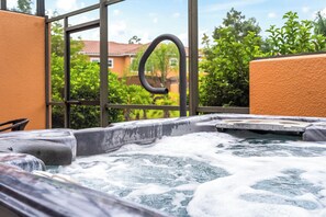 A hot tub with a view of a residential area through large windows. - Beachside Vibes |2BR/2BATH Townhouse | Near Disney (Kissimmee)