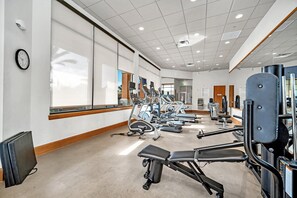 A gym with cardio machines, weight stations, and a large mirror wall.