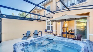 A hot tub area with chairs and a table, a covered patio, and a building with a balcony. - Waterfront/Minutes to Disney/Waterslides & Pool (Kissimmee)