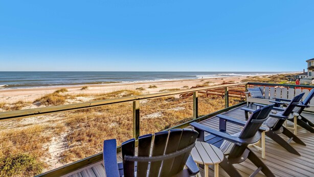 Una terraza con sillas y mesas que da a una playa.
