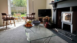 Una sala de estar con chimenea, televisor y comedor con sillas y mesa.