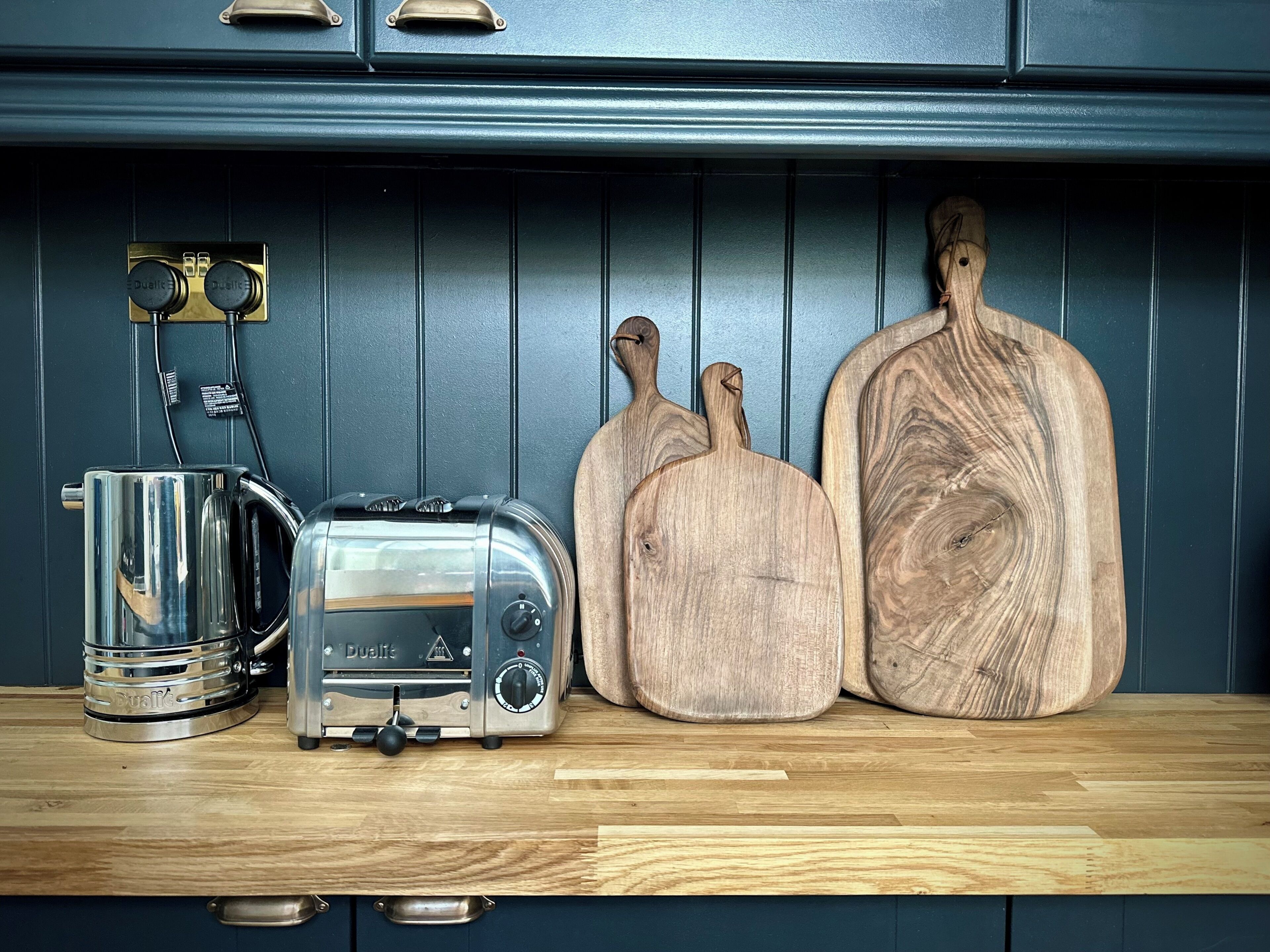 A kitchen counter with a toaster, a kettle, and two wooden cutting boards.