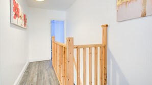 A hallway with wooden railings, a light fixture, and a door leading to another room.