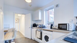 A compact kitchen with a washing machine, a microwave, and a toaster.