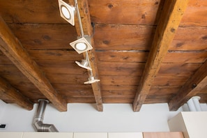 Een houten plafond met zichtbare balken en een centraal hanglamp.