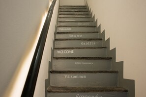 Un escalier dont les marches sont marquées de panneaux indiquant leur numéro dans plusieurs langues, dont l’anglais, le français et l’allemand.
