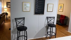 Une pièce avec deux chaises noires, un tableau noir fixé au mur sur lequel sont écrits les jours de la semaine, et des tableaux encadrés.