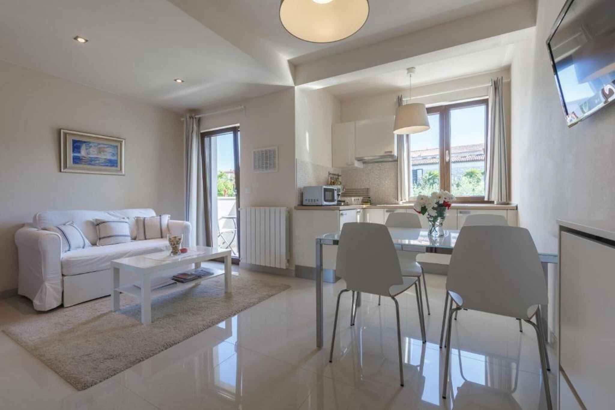 Ein modernes Wohnzimmer mit einem weißen Sofa, einem Couchtisch und einem Essbereich mit Stühlen und einem Tisch.