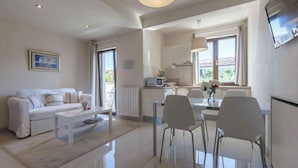 Ein modernes Wohnzimmer mit einem weißen Sofa, einem Couchtisch und einem Essbereich mit Stühlen und einem Tisch.