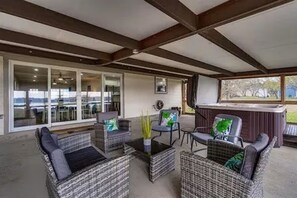 A covered outdoor seating area with wicker furniture and a hot tub. - Luxurious, fishing, riding boat and fun at Richland Chambers at Lake front home (Corsicana)